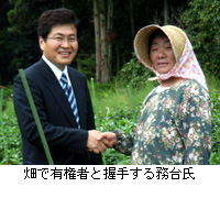 写真：畑で有権者と握手する務台氏